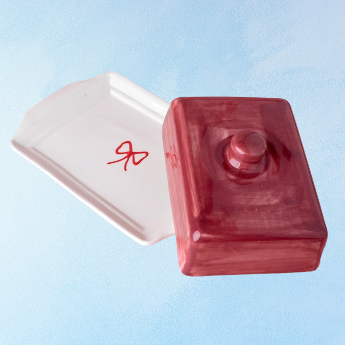ceramic butter dish with a white bottom, bow detail, and burgundy lid