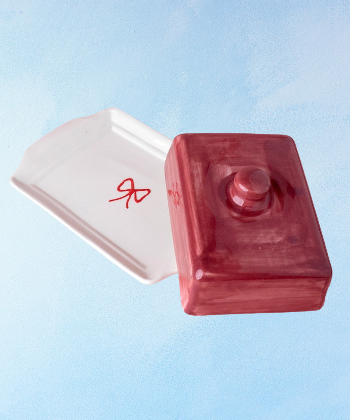 ceramic butter dish with a white bottom, bow detail, and burgundy lid