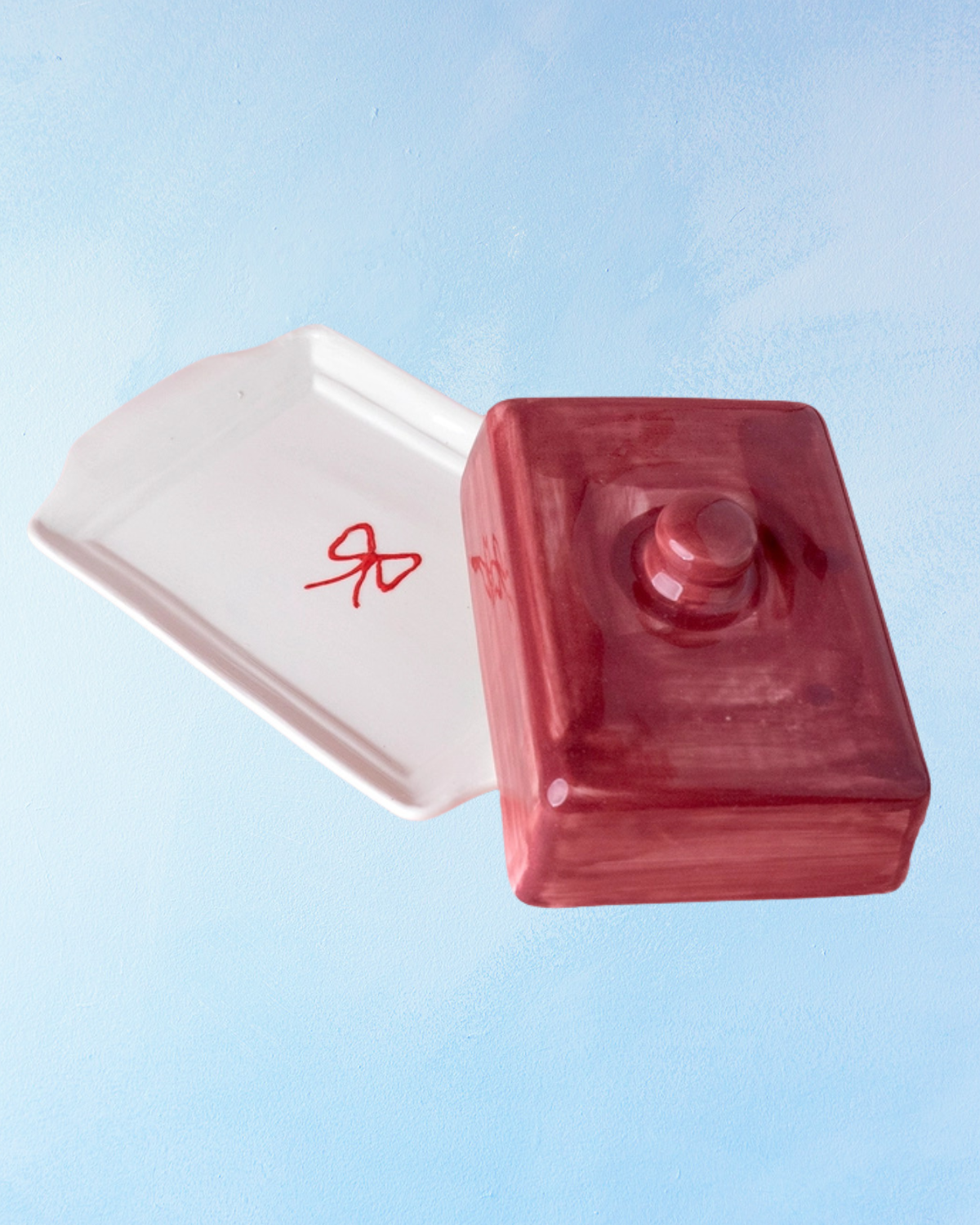 ceramic butter dish with a white bottom, bow detail, and burgundy lid