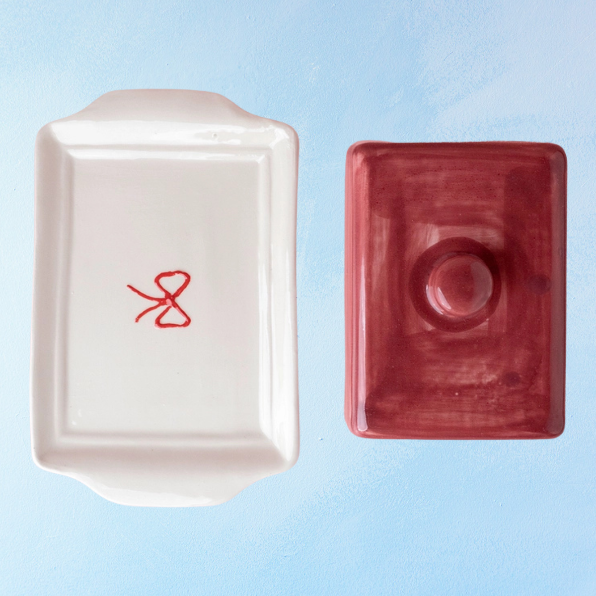 ceramic butter dish with a white bottom, bow detail, and burgundy lid