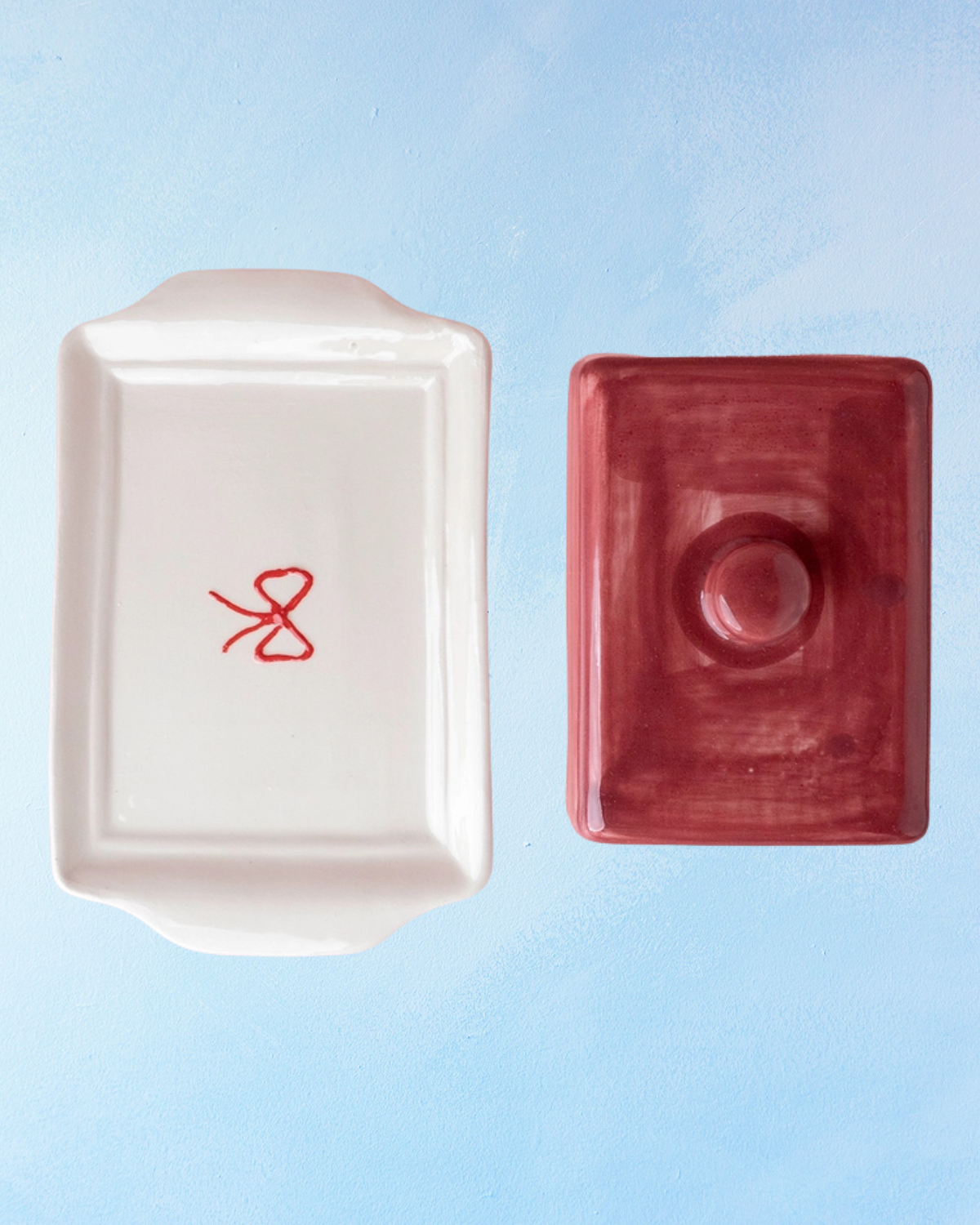 ceramic butter dish with a white bottom, bow detail, and burgundy lid