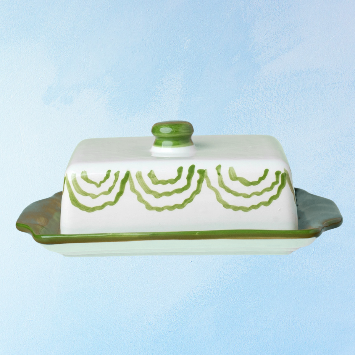 ceramic butter dish with a green bottom base and white lid with green accents
