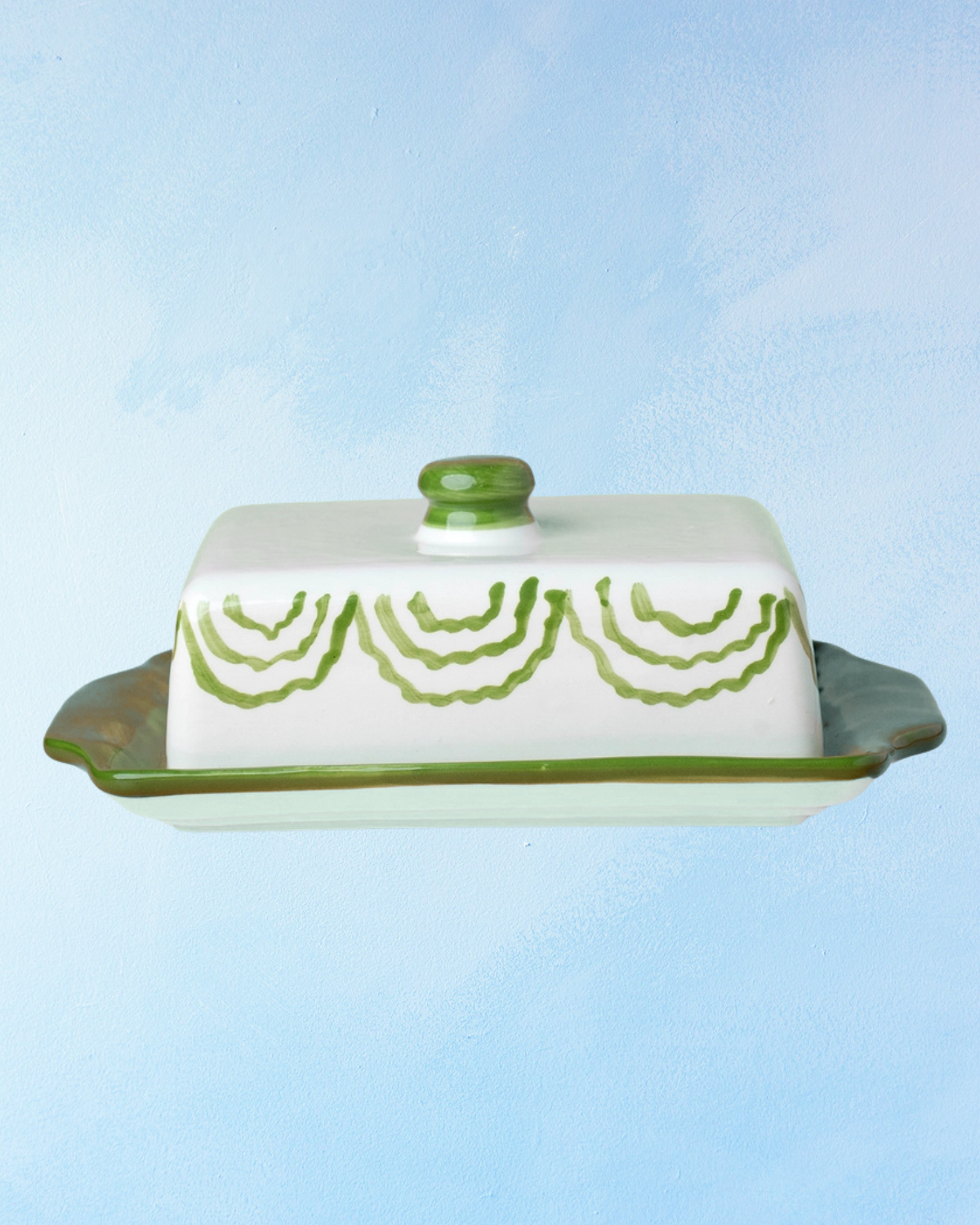 ceramic butter dish with a green bottom base and white lid with green accents