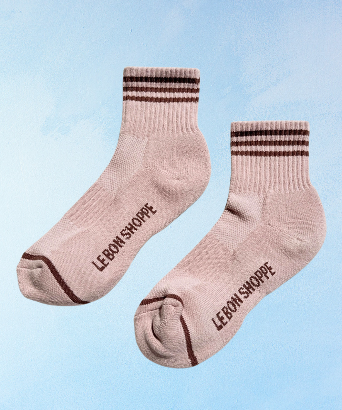 Pair of pink socks with brown stripes and 'LEBON SHOPPE' branding on a light blue background