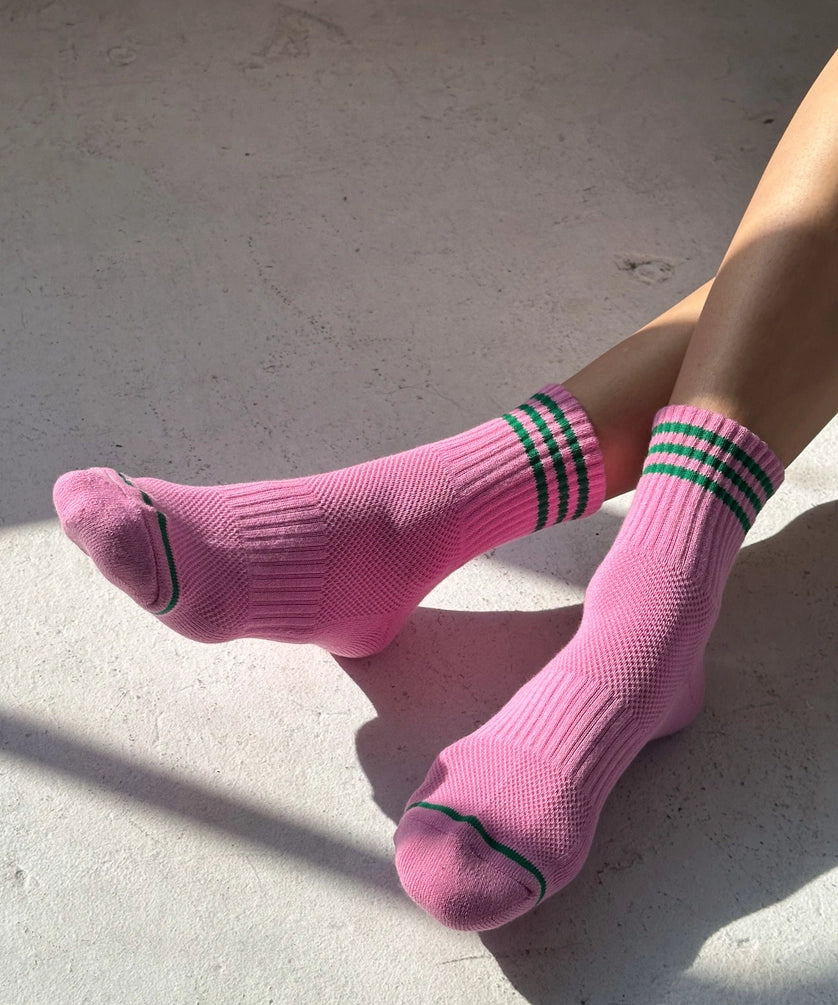 Person wearing pink socks with green stripes on a concrete surface