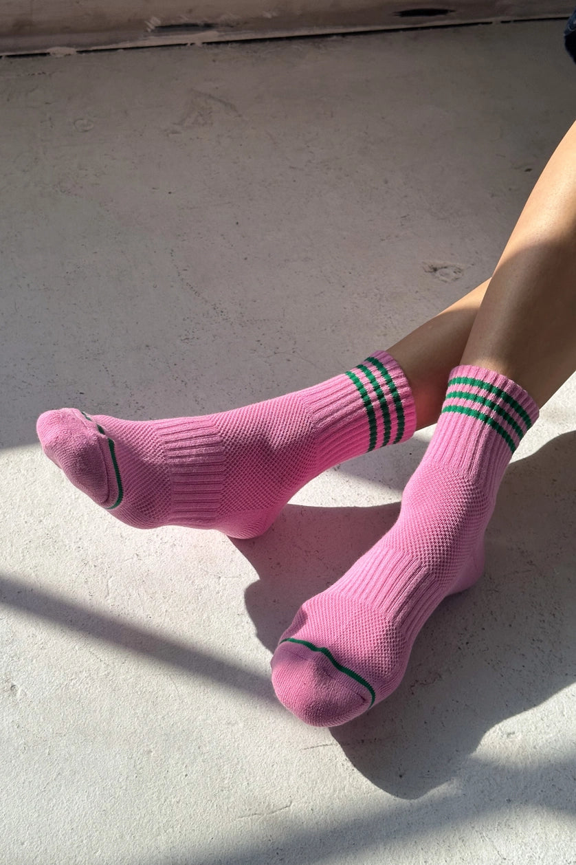 Person wearing pink socks with green stripes on a concrete surface