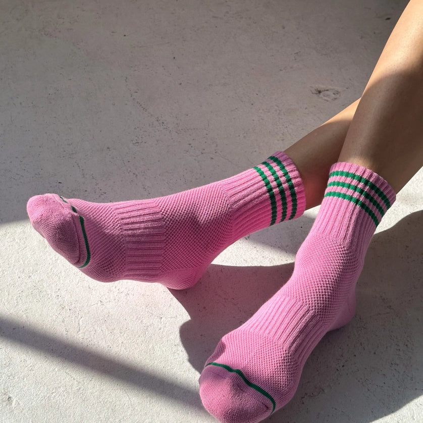 Person wearing pink socks with green stripes on a concrete surface