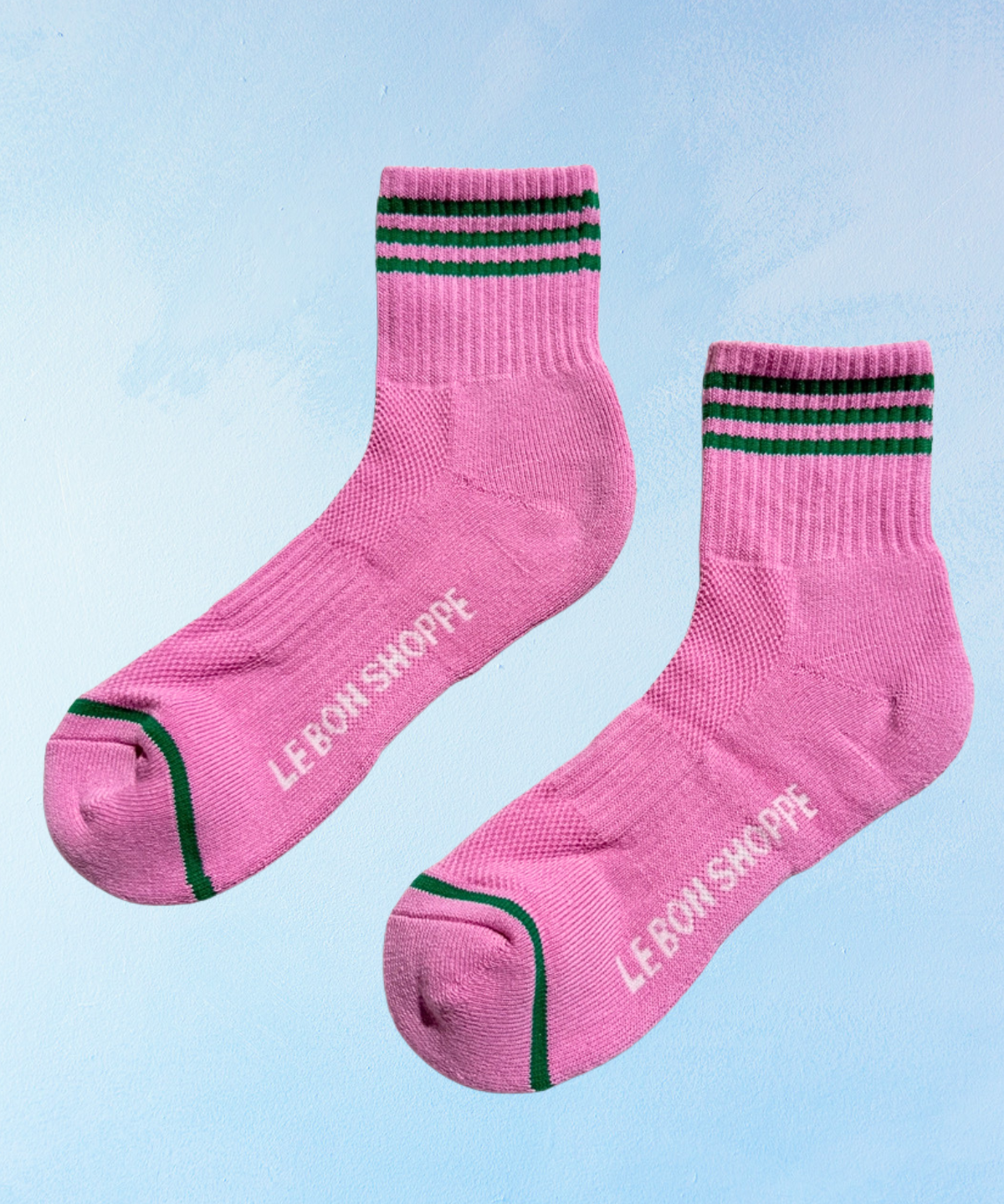 Pink socks with green stripes and 'LE BON SHOPPE' branding on a light blue background