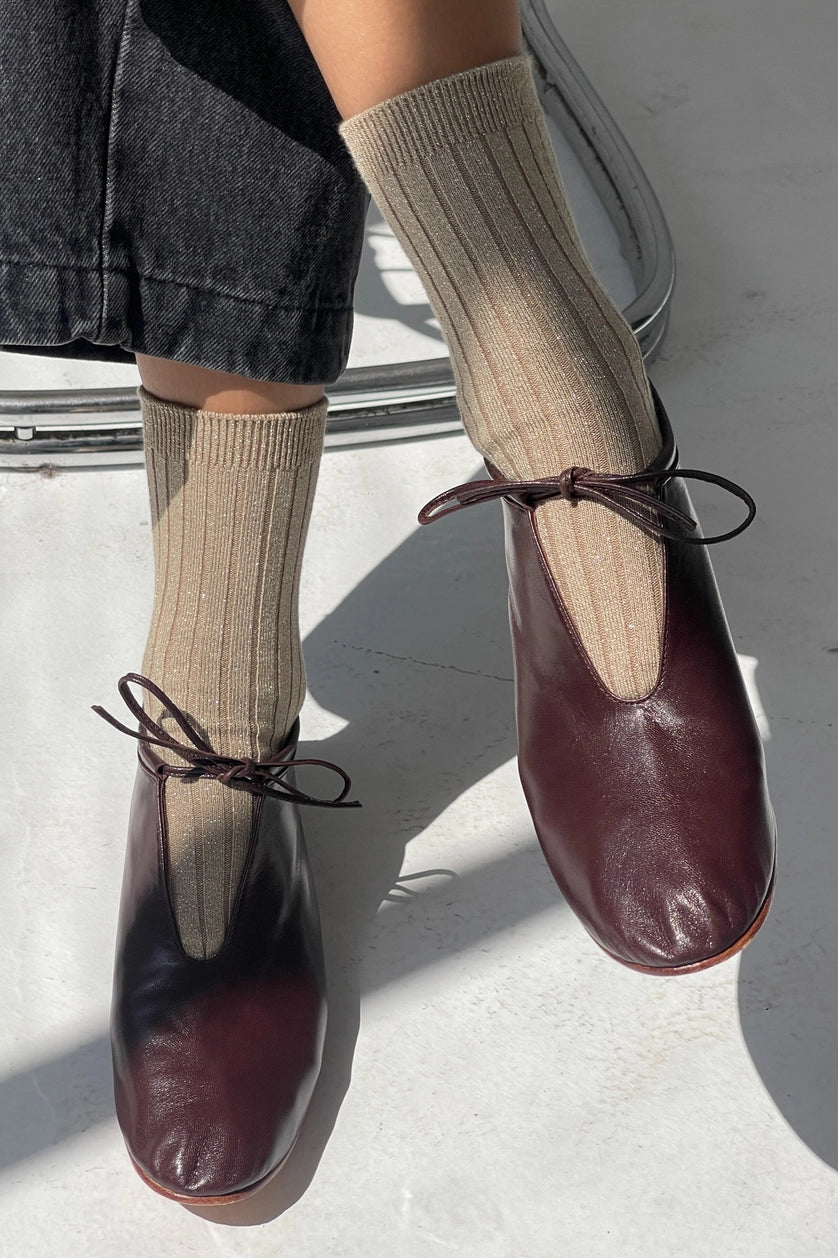 Person wearing beige ribbed socks with brown closed toe shoes