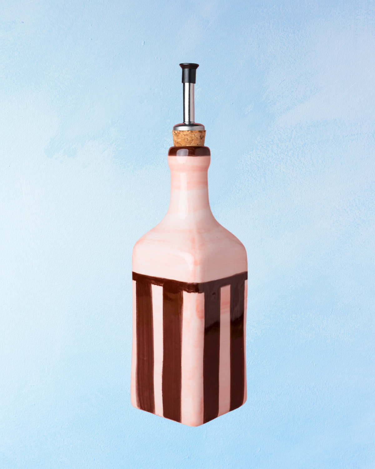 ceramic oil dispenser with square shape, pink base and brown stripes. There is a cork stopper with stainless steel spout inside.