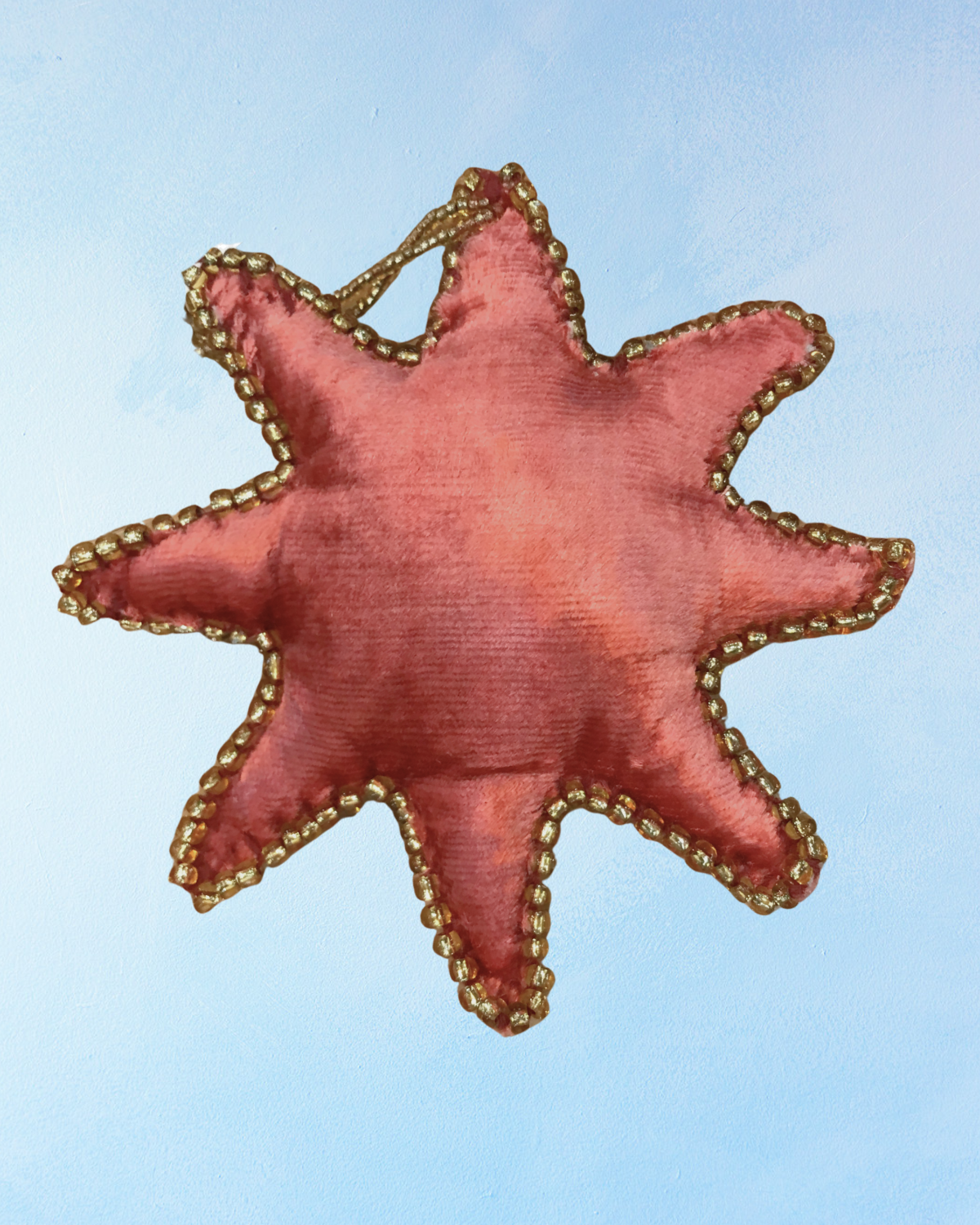 eight pointed star ornament made from red velvet with gold beaded trim