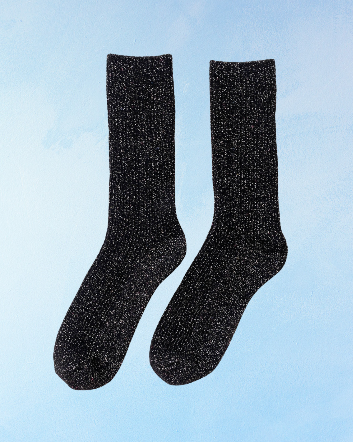 Pair of glittery black socks on a light blue background. Le Bon Shoppe Winter Sparkle in Starry Night.