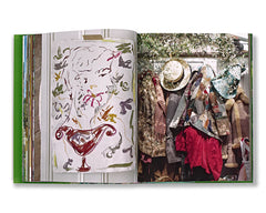 A full page spread from A Kind of Magic by Luke Edward Hall with a painting and a collection of hats and jackets hanging on a wall.