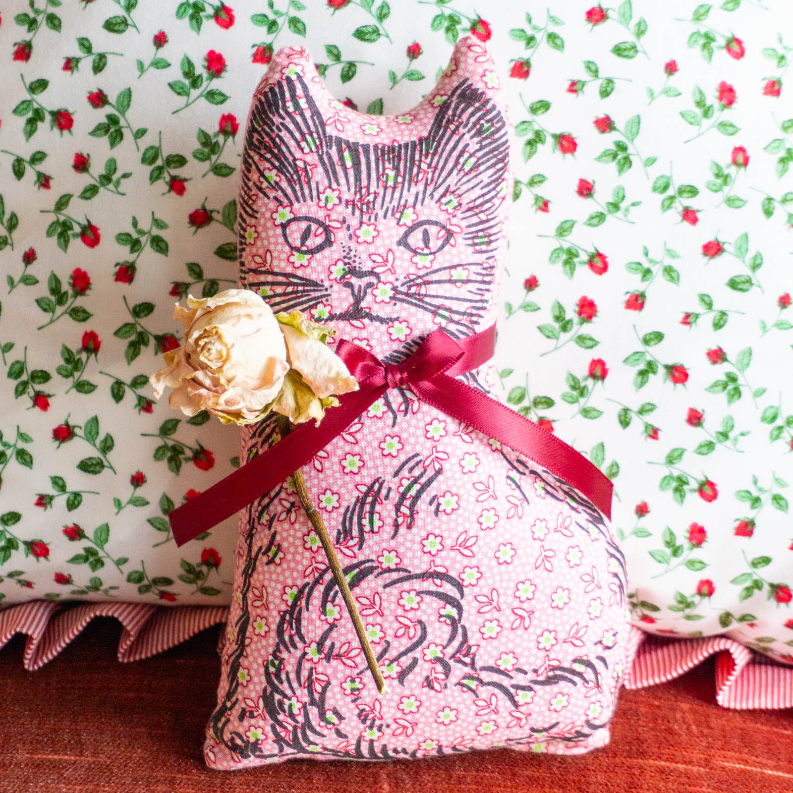 Calico cat balsam pillow in pink with a red ribbon