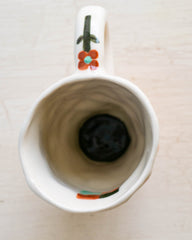 The inside of a ceramic hand made mug with wavy orange stripes and a little flower on the handle