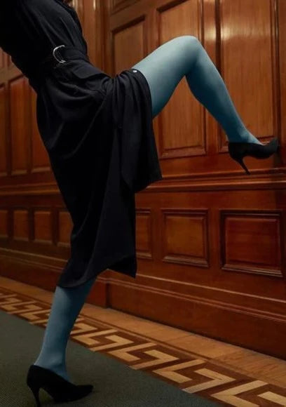 A model in a black dress wearing Svea semi-sheer dusty blue tights