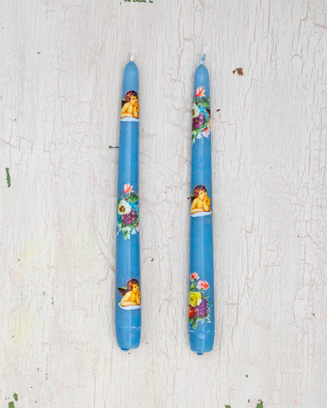 Two blue taper candles with delicate cherub and flower details