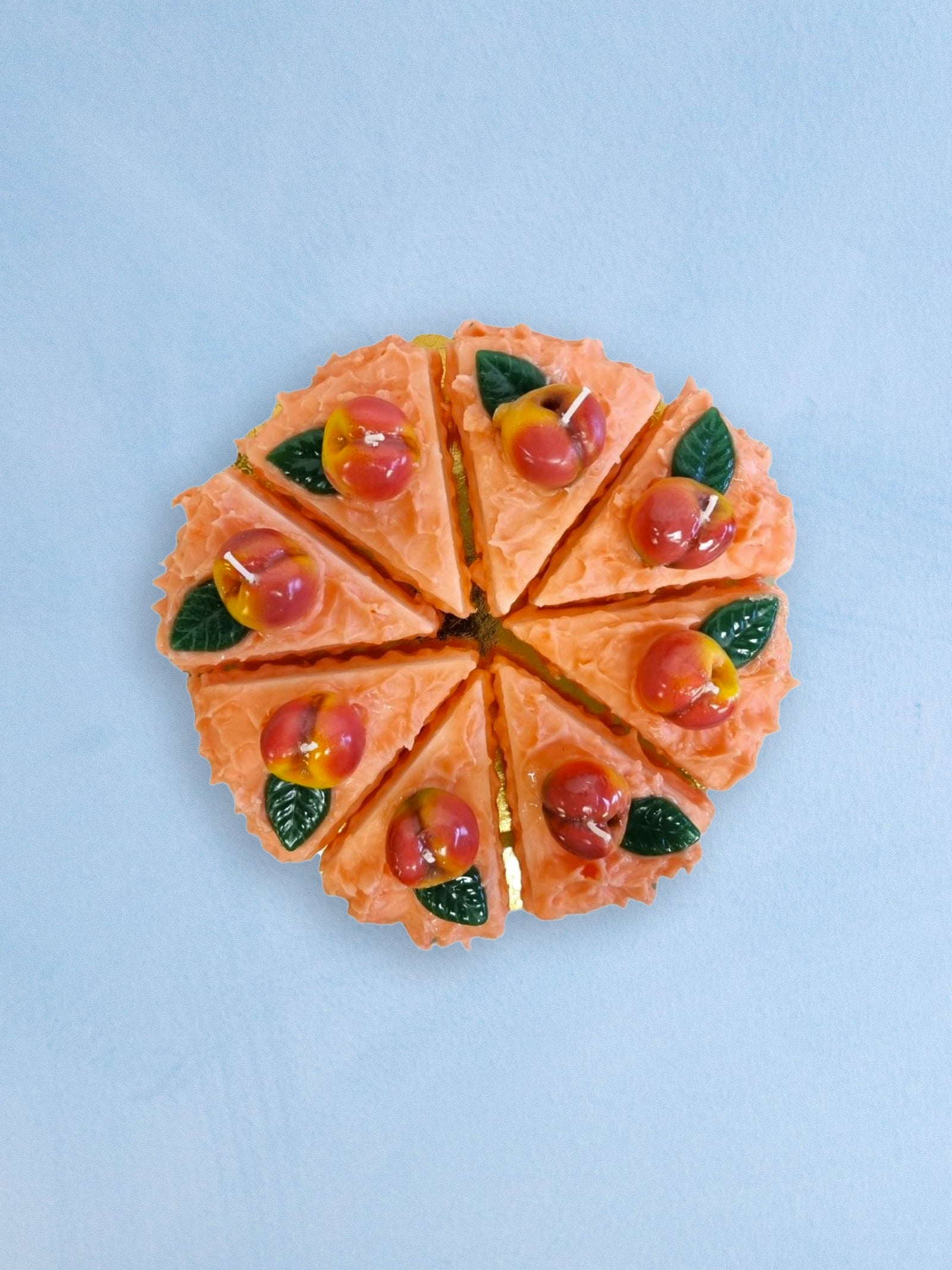 candles that are slices of peach cake arranged into a full cake