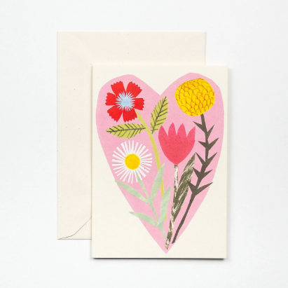 A greeting card featuring beautiful bouquet of flowers layered on a soft pink heart.