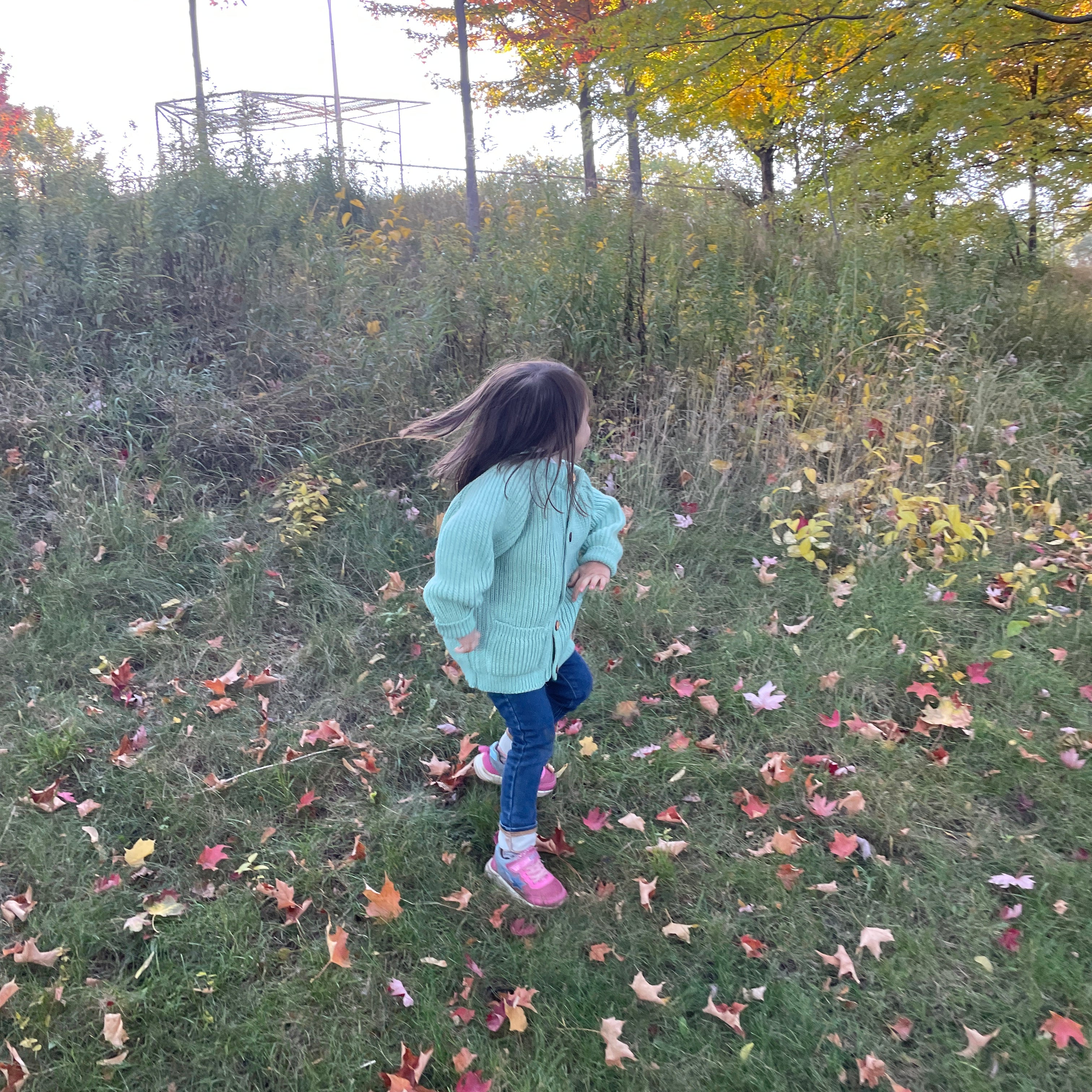 A child running in a teal children's wool cardigan with a crew neck collar, patch pockets, english rib knit stitch body, and a finely detailed raglan sleeve