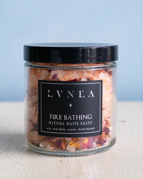 Clear glass jar filled with large pink Himalayan bath salts and dried rose petals by Lvnea.