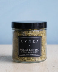 Clear glass jar filled with pale green coloured coarse bath salts and dried cedar leaves by Lvnea.
