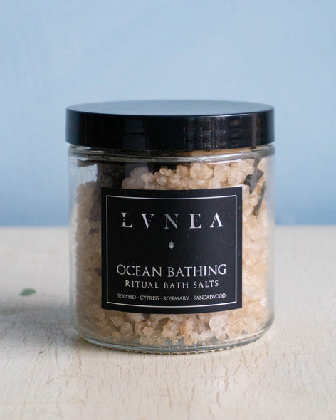 Clear glass jar filled with coarse sea salt bath salts and dried rosemary by Lvnea.