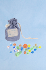 A blue cloth bag of Moulin Roti marbles and the marbles displayed in front