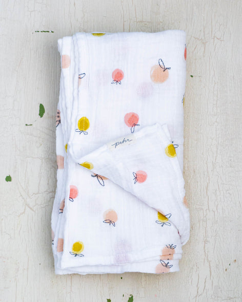 White organic cotton baby swaddle blanket featuring a delicate fruit design in pale peach, pink and yellow..
