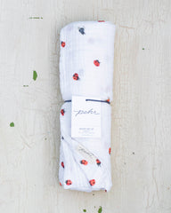 White organic cotton baby swaddle blanket featuring a red and black ladybug design.