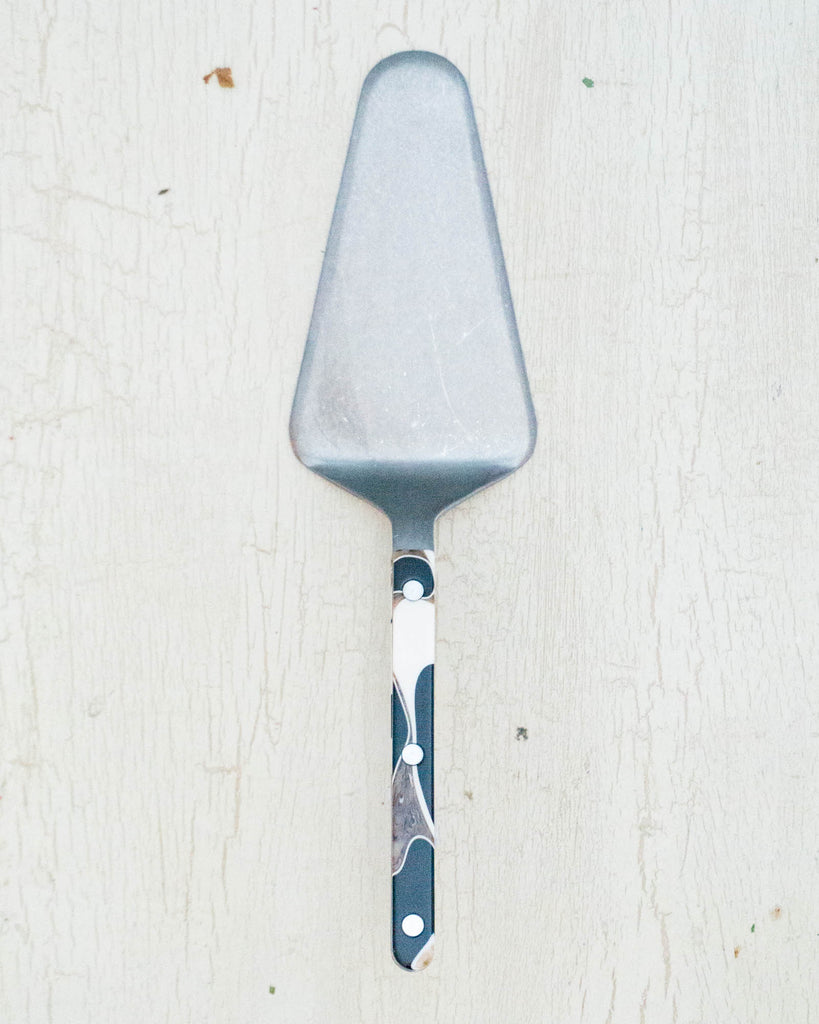 Stainless steel butter spreader with black marbled acrylic handle and visible rivets: By Sabre Paris.